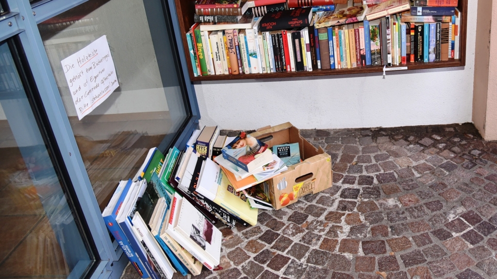 Weil die vermutlich gestohlene Bücherkiste immer noch fehlt, stehen die Bücher unterhalb des öffentlichen Bücherregals wieder auf dem Boden.