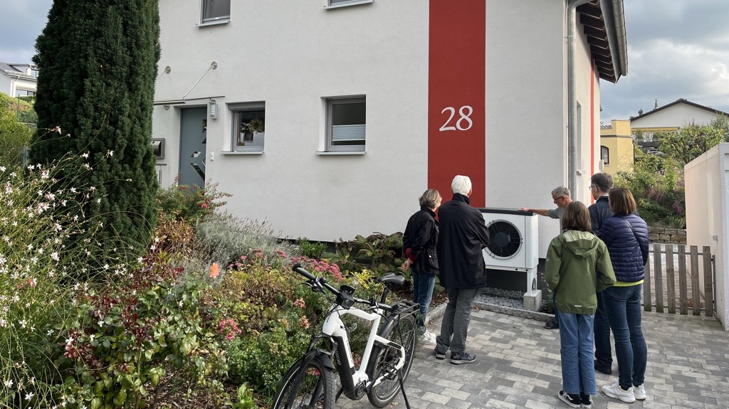 Menschen begutachten eine Wärmepumpe vor einem Wohnhaus. Bild: KliBA. 