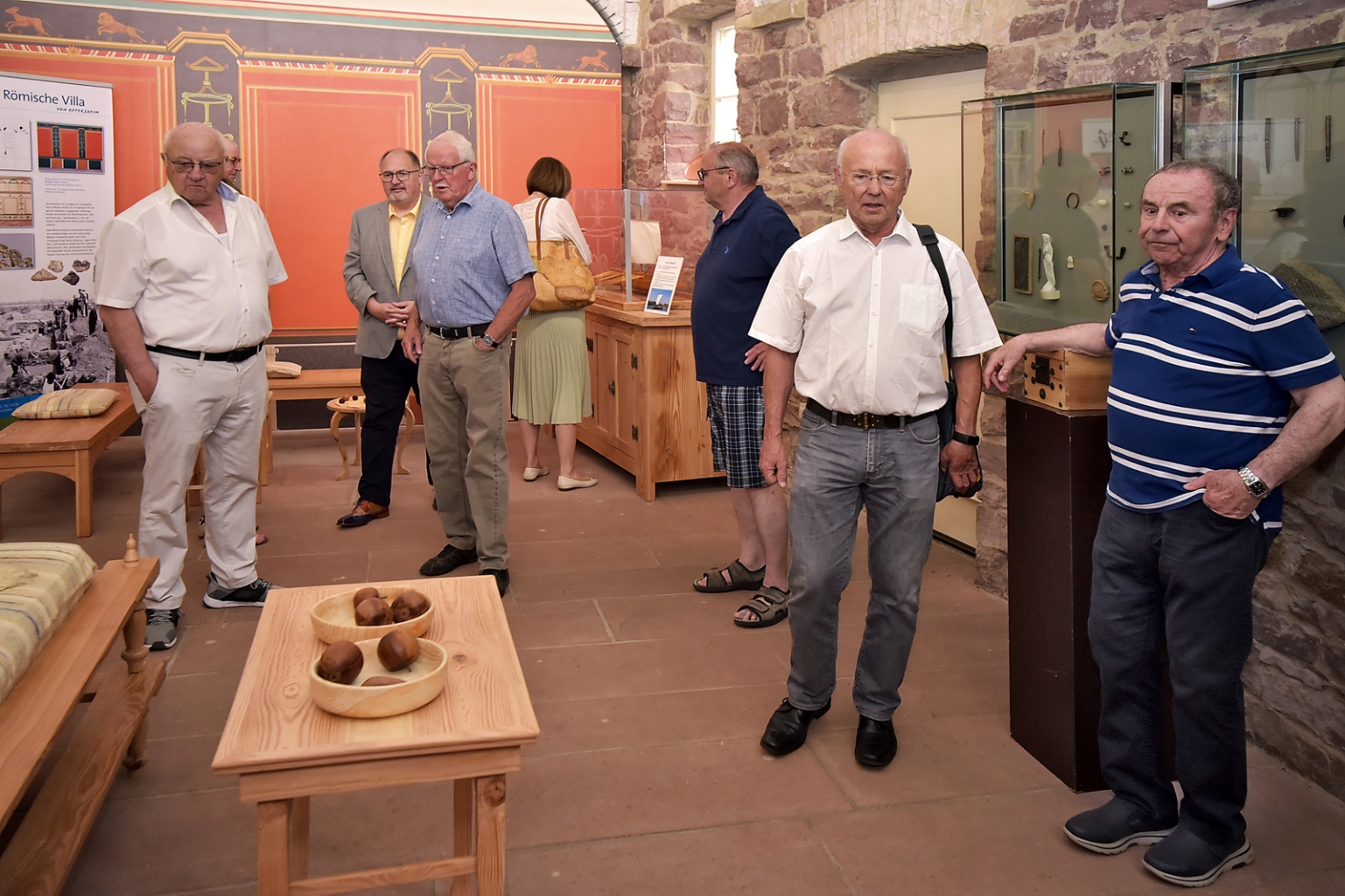 Ehrenbürger, Gemeinderäte und der Ehrenvorsitzende des HuKO schauen sich in der Römerstube um.
