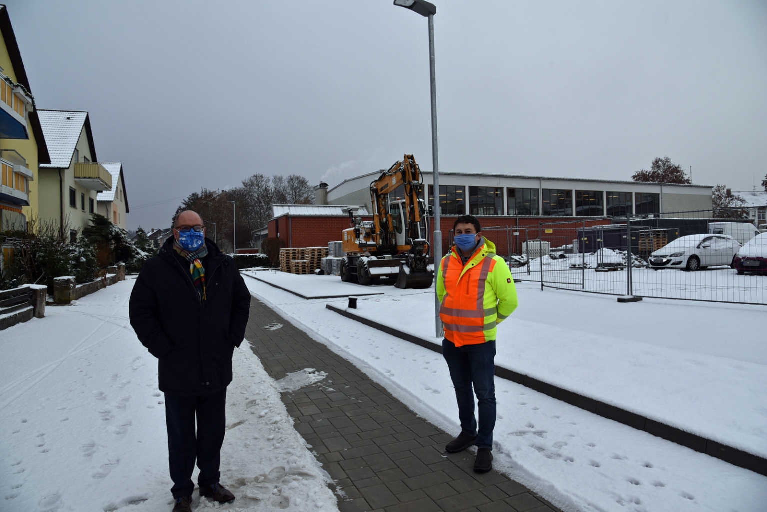 Bürgermeister Jens Geiß und Alexander Kulagin vom Bauamt begutachten die sanierte Straße im Schnee.