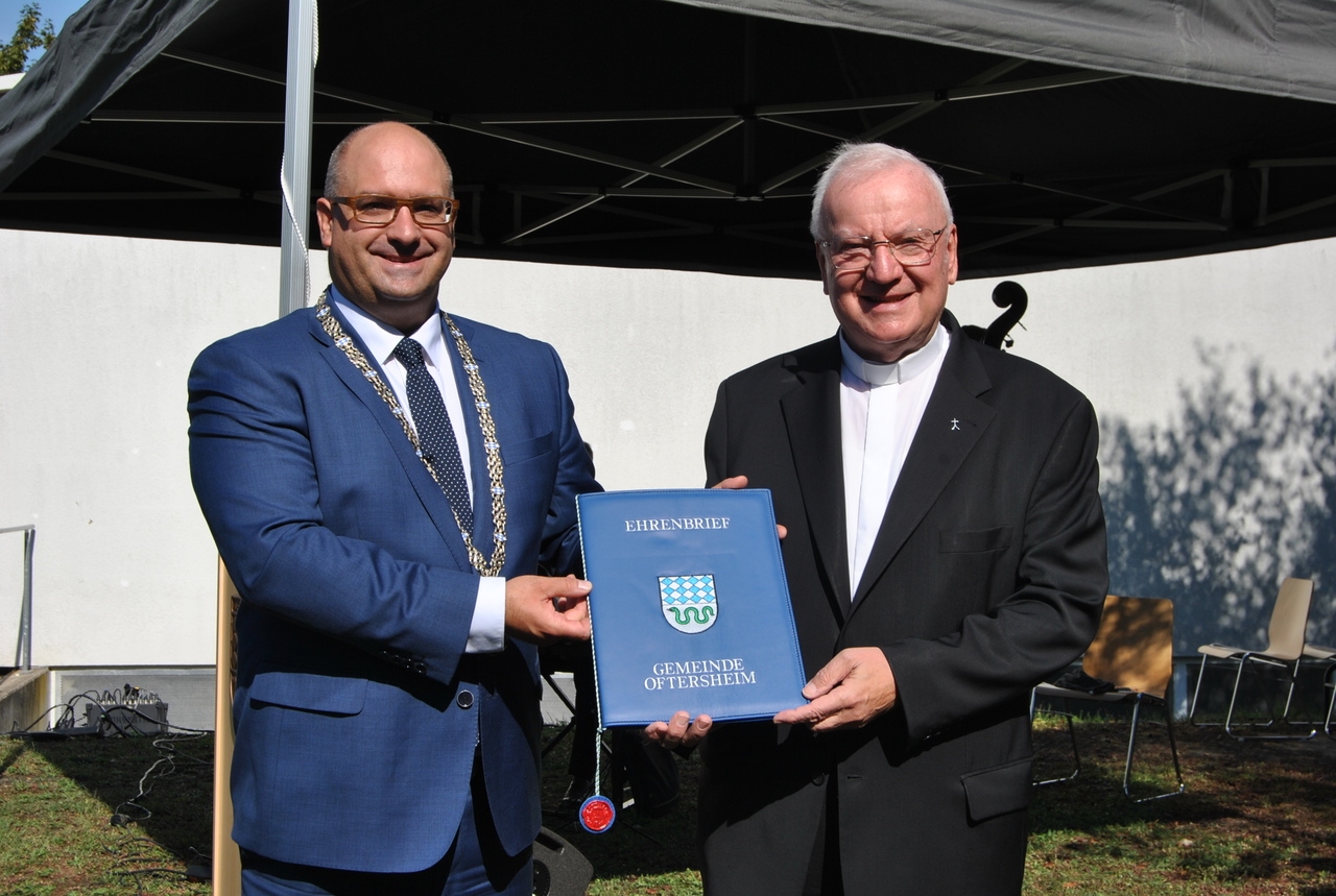 Bürgermeister Jens Geiß überreicht Pfarrer Wolfgang Gaber den Ehrenbrief.