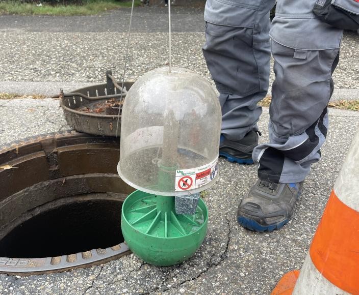 Eine Rattenköderbox wird gleich in einen offenen Kanal hinabgelassen. Eine Rattenköderbox wird gleich in einen offenen Kanal hinabgelassen.
