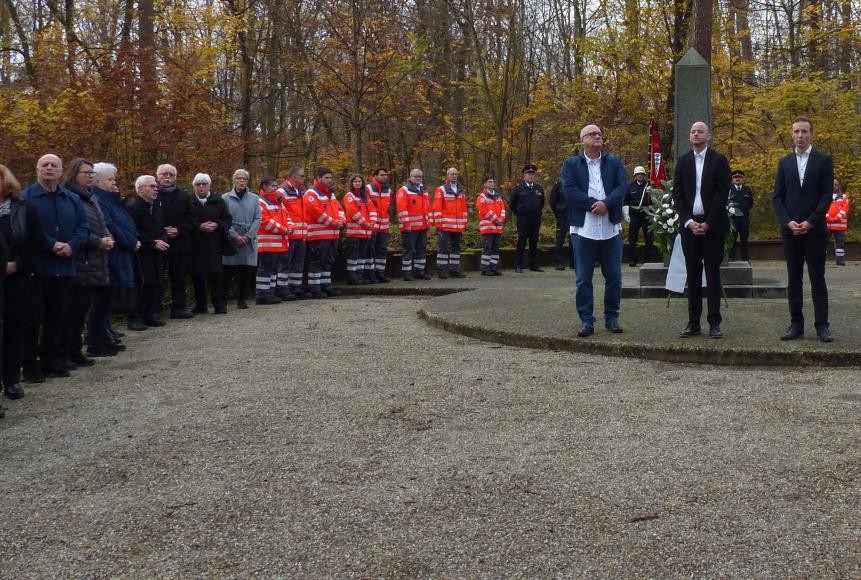 Im Vordergrund Peter Mark, Bürgermeister Pascal Seidel, Pfarrer Dr. Simon Layer, im Hintergrund Abordnungen der Feuerwehr und des DRK sowie Bürger*innen