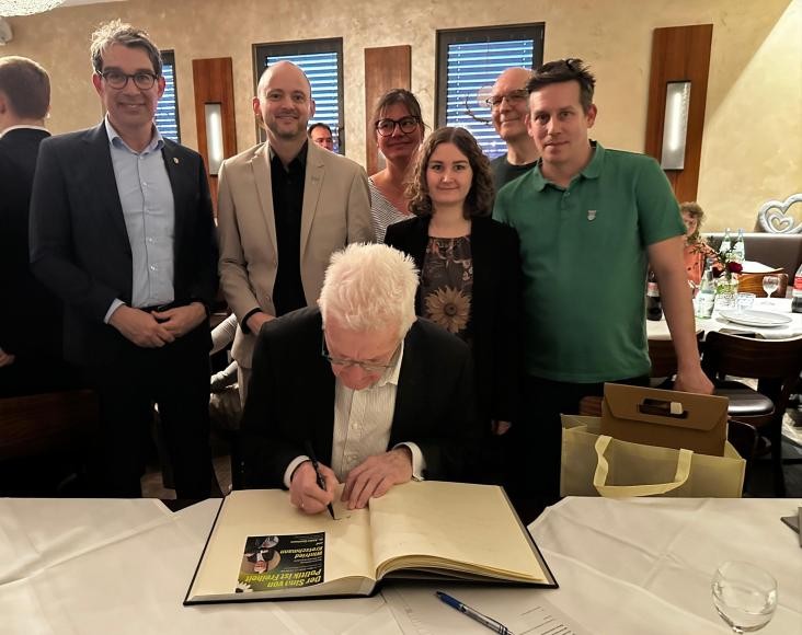 Ministerpräsident Winfried Kretschmann trägt sich ins Goldene Buch ein.