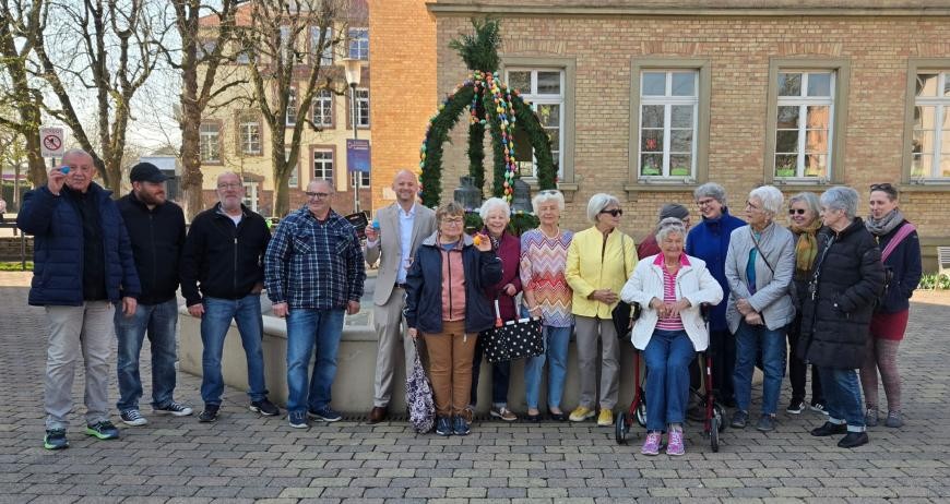 Männer und Frauen des Arbeitskreises "Volkskunde und Brauchtum" und des Heimat- und Kulturkreises zusammen mit Bürgermeister Pascal Seidel vor dem Brunnen mit der Osterkrone
