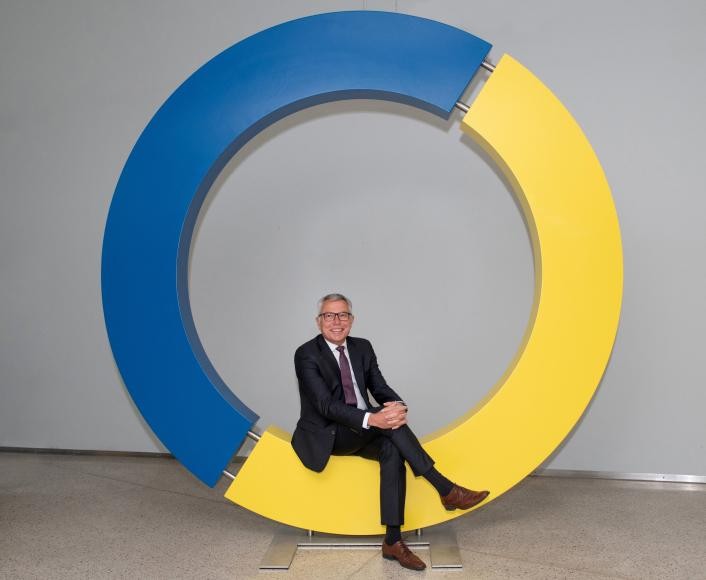 Landrat Stefan Dallinger sitzend auf dem Kreislogo des Rhein-Neckar-Kreises
