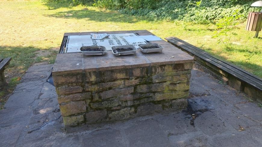 Benutzte Einweggrills an der Grillhütte. Die Grillstelle ist sichtbar gesperrt.